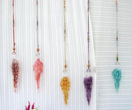 Solid sculpted hot formed feathers. Hangs from varying length leather and beaded cords. Suspend in window as a suncatcher.  Approx. 4.5"-7" L