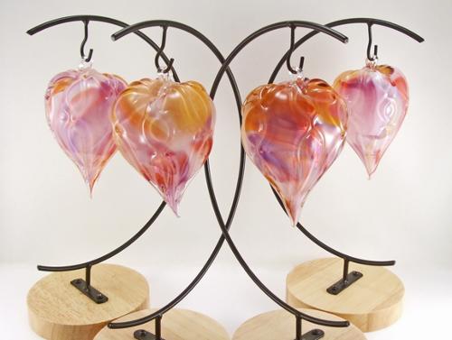 Blown glass, heart-shaped ornament with a combination of colors swirled throughout interior. Surface texture is ribbed with a subtle "hugs-n-kisses" xoxo pattern. Approx size 3-4" h x w